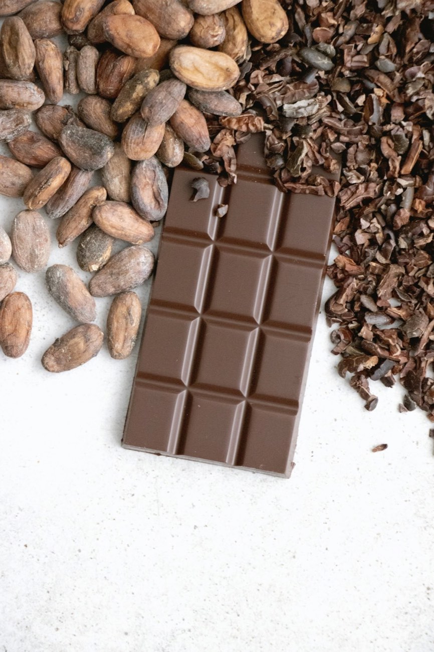 Barra de chocolate ao lado de amêndoas e nibs de cacau